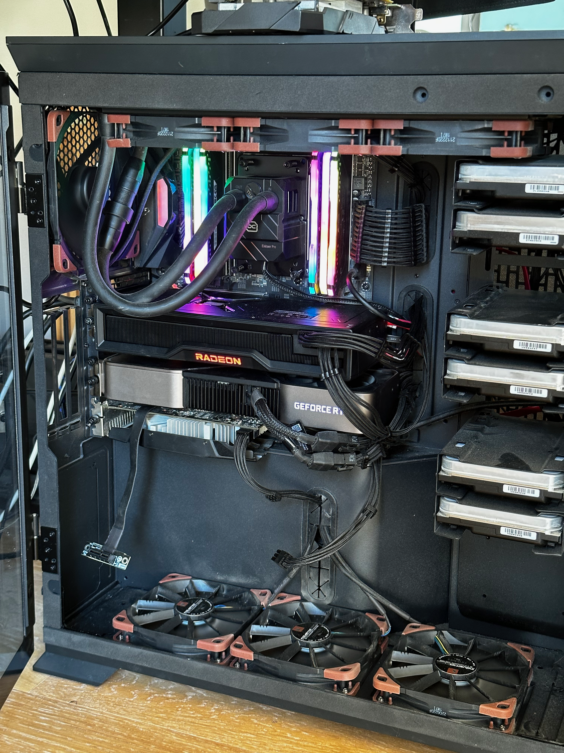 Photo intérieure du châssis noir de Gath, montrant un système de refroidissement liquide, trois cartes graphiques et 6
disques durs montés en façade. Des ventilateurs sont disposés en bas, en haut, et à l’arrière du
boîtier.